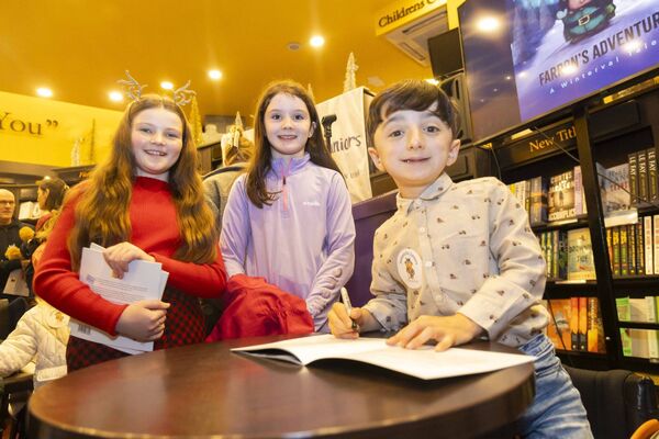 Adam King signs his book, ‘Farron’s Adventure’, for Niamh Butler and Ella Raftice, at the launch event in The Book Centre on Saturday. Photo: Patrick Browne