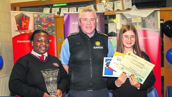 Garda David Browne presenting the award for ‘Keeping the Community Safe’ to 5th year students Mirriam Milanzi and Aleksandra Balant. Photo: John Power