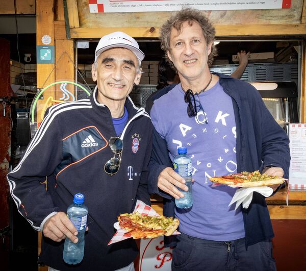 Spanish tourists Luis and David enjoy slices of pizza.